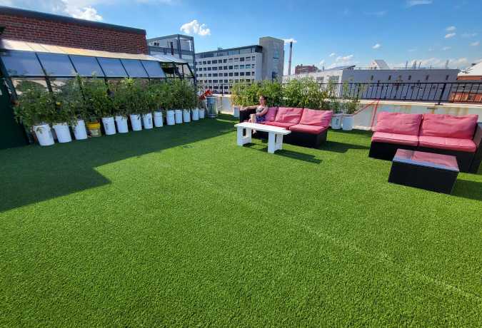 Woman relaxing in artificial grass lounge area of rooftop reds